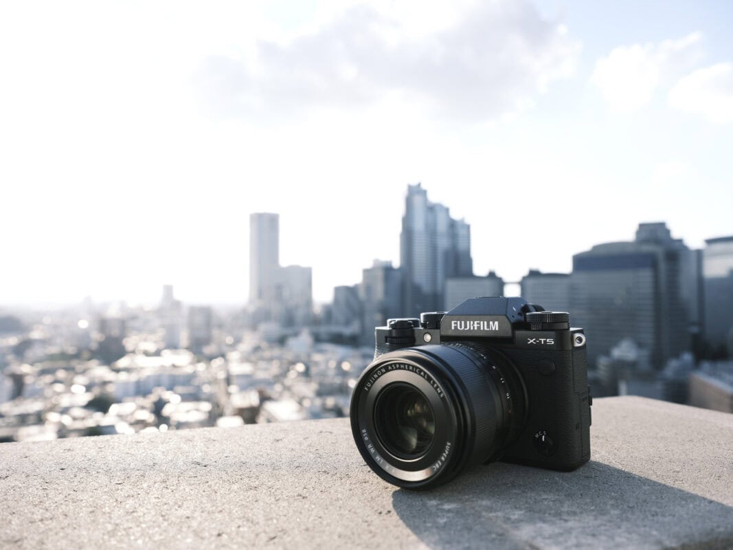 Fujifilm X-T5 Kamera auf einem Dach mit Stadtblick im Hintergrund.